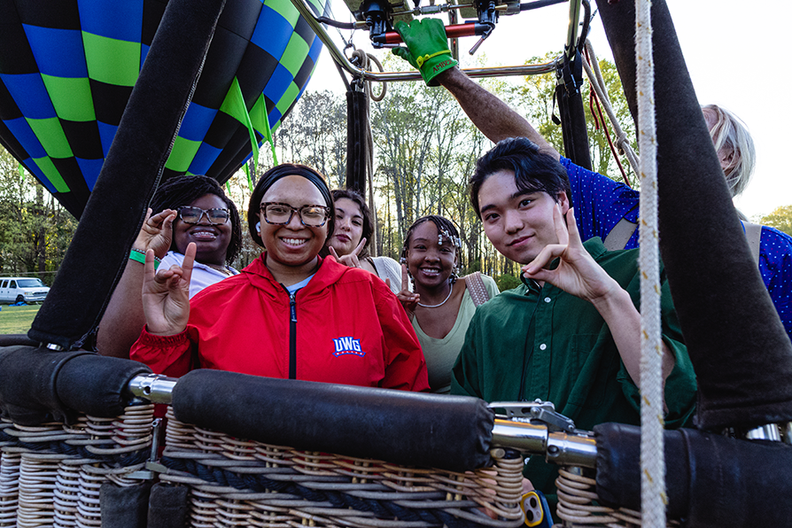Students at Lantern Festival in a hot air balloon smiling with the hand wolves sign