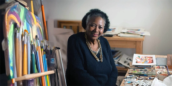 older woman sitting by art supplies