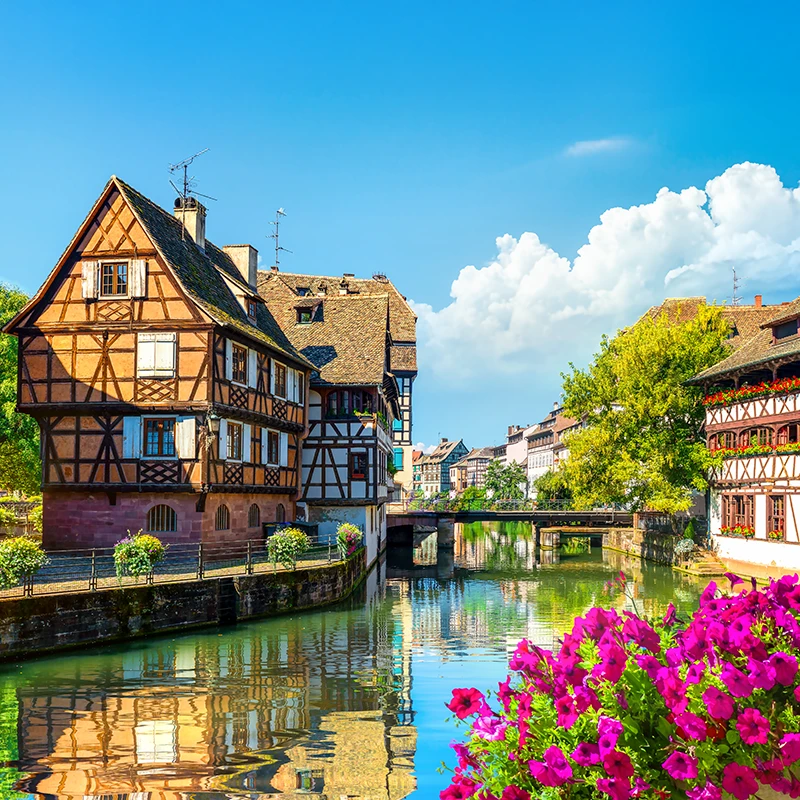 boat with people going down a canal lined with tutor-style houses in Strasbourg, France