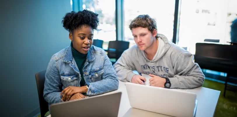 two students studying on laptops