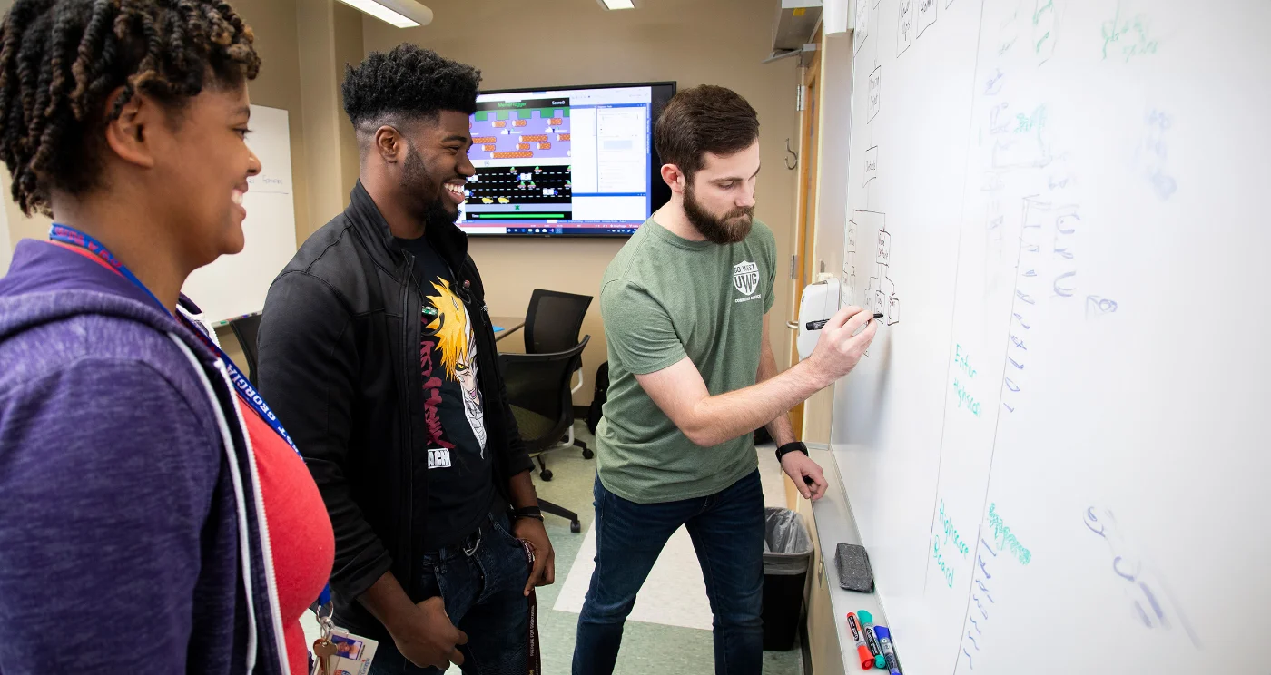 students writing on dry-erase board