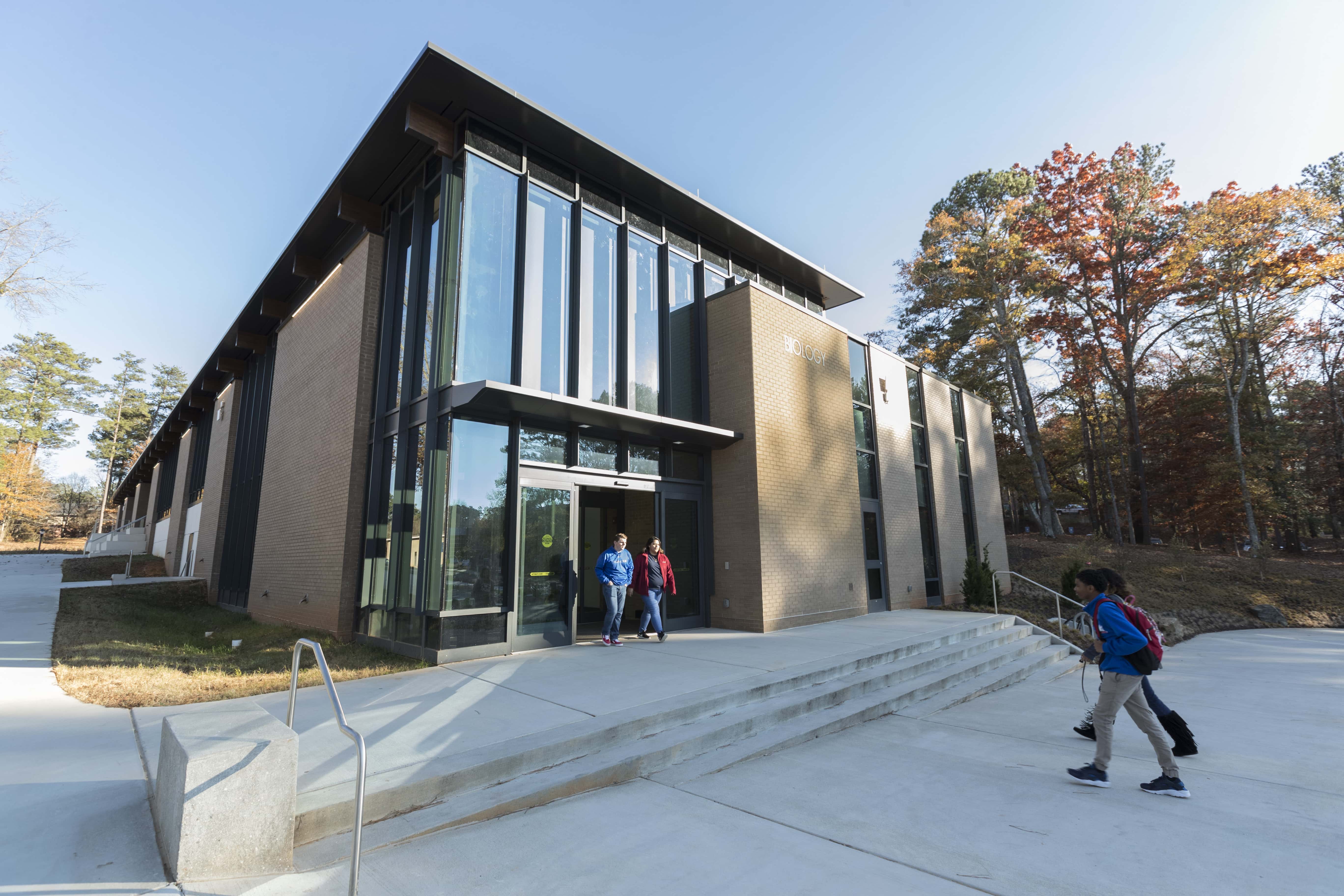 Exterior view of the Biology Building on the University of West Georgia campus, featuring a modern glass entrance and students walking near the main entrance.