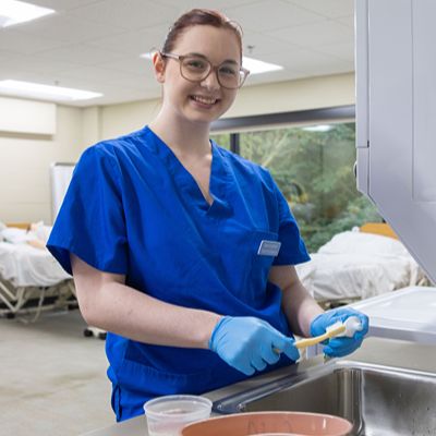 cna student brushing teeth in clinical lab