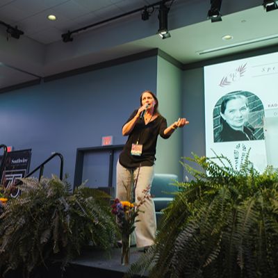 WILL 2025 Conference A woman with a microphone addressing the audience at the WILL 2025 Conference.