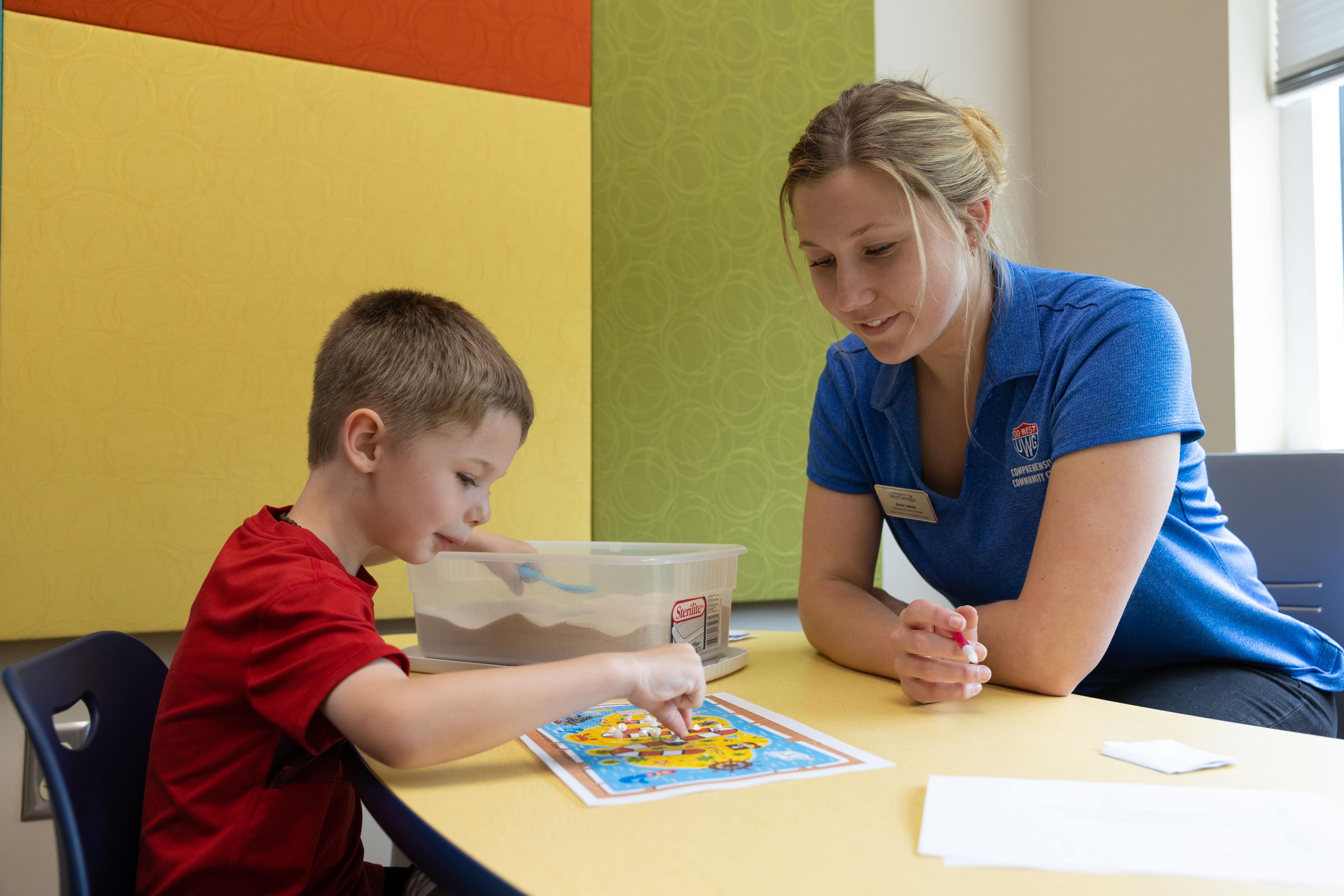 Teaching sitting at the table with a young student.