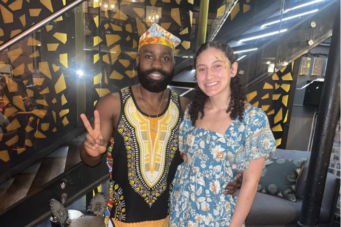 women standing with a man dressed in traditional South African clothing