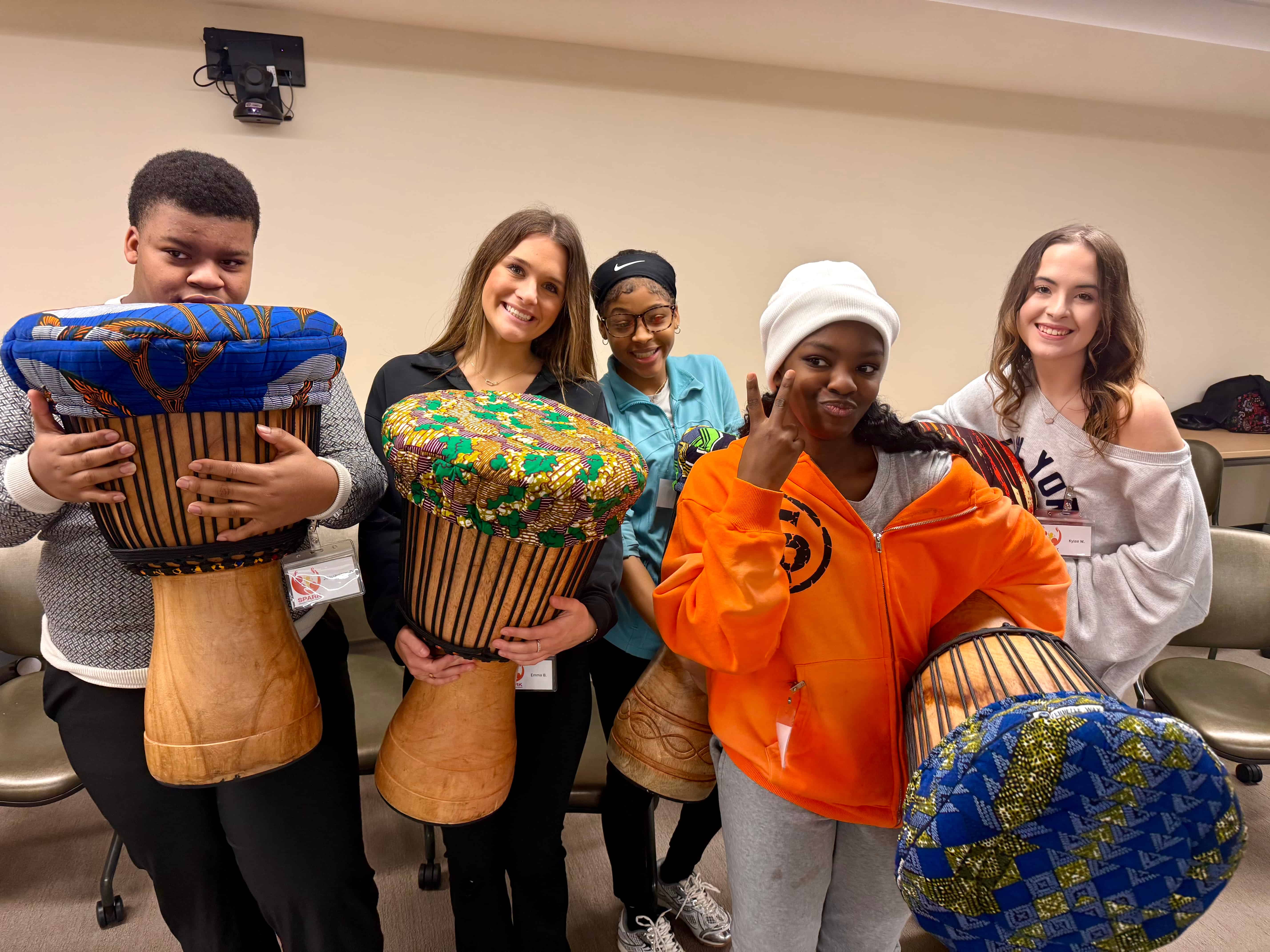 Students standing together, holding drums with patterned covers posing for a photo.