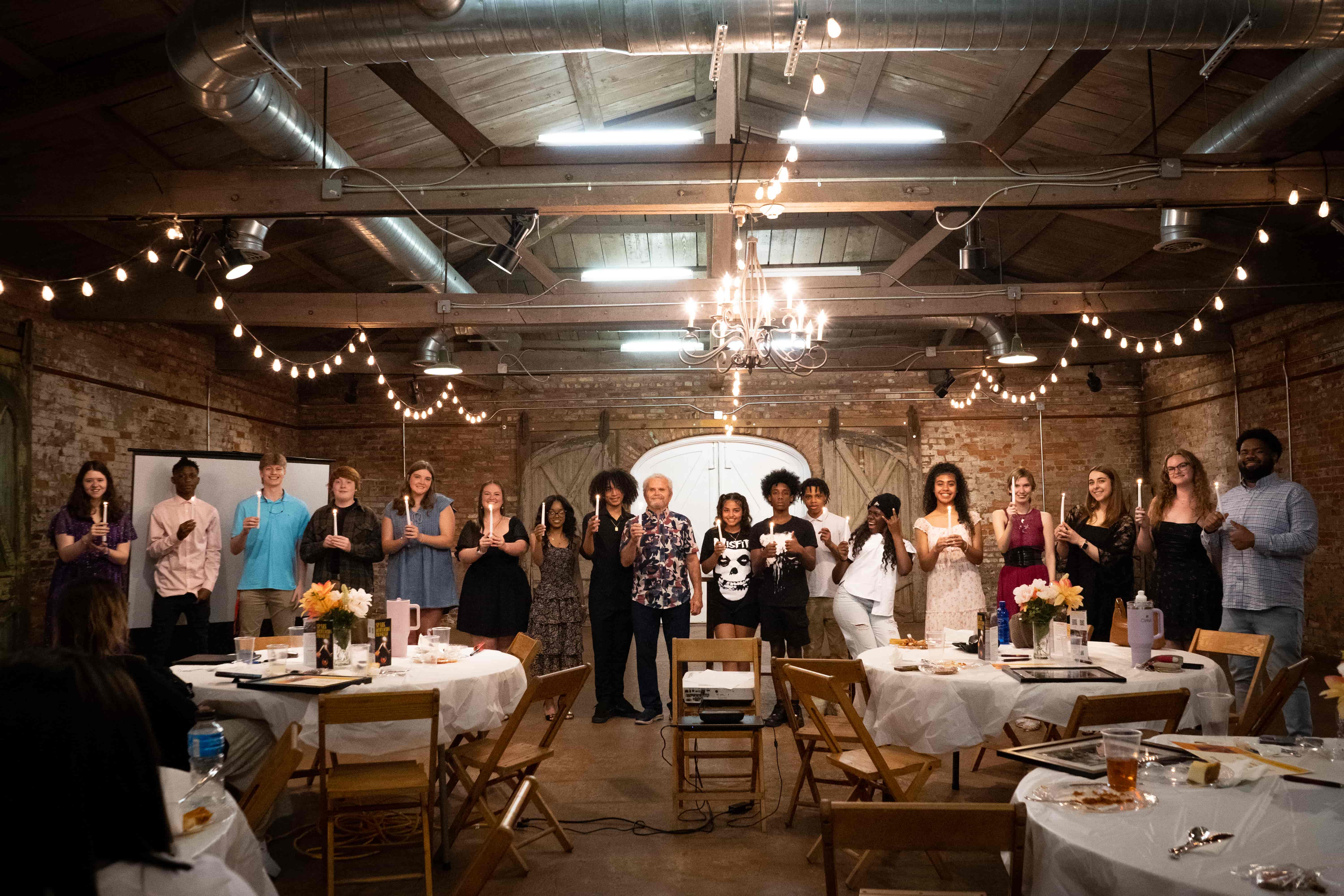 Group photos of program participants standing together, each holding a candle.