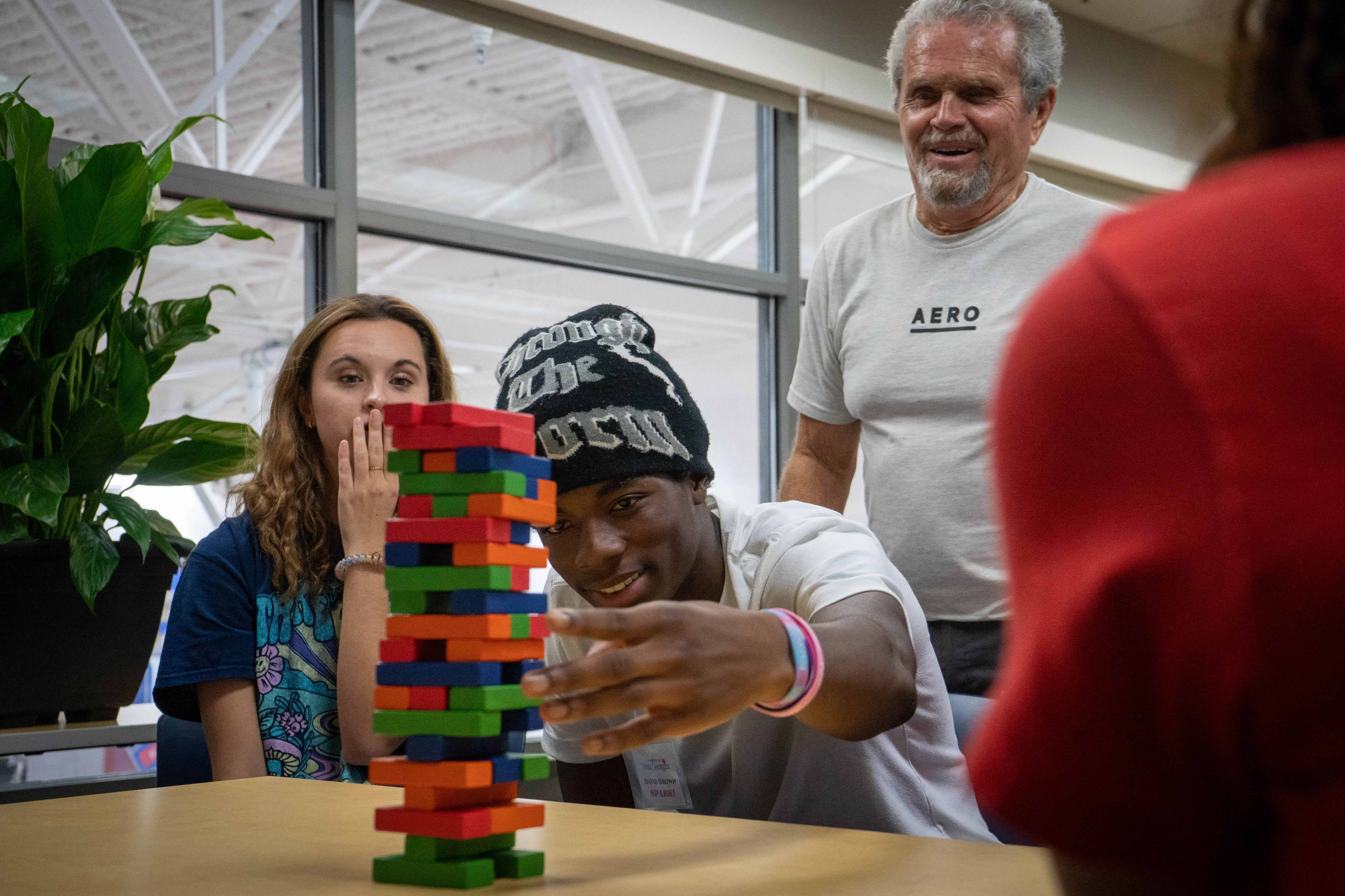 Students sitting around a table playing jenga.