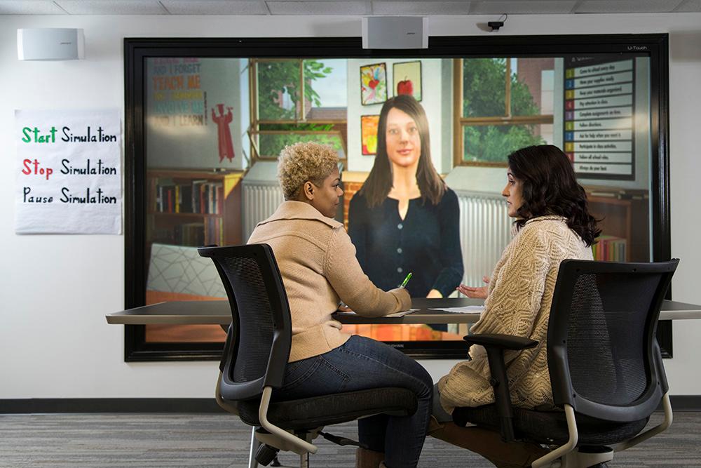 Two people in front of a simulation in the UWGLive main simulations learning area