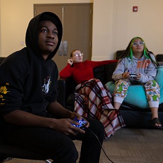 Three students playing games in a common area. 