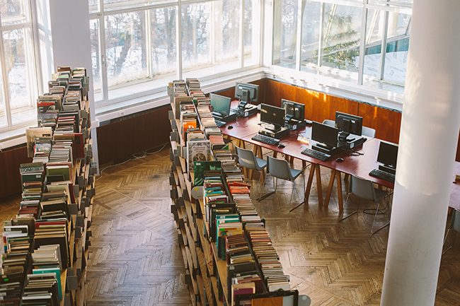 Photograph of a high angle view of rows of books in a library with a computer lab adjacent