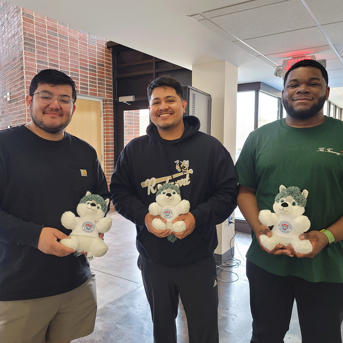 Three students holding the plush wolfies they made in Newnan