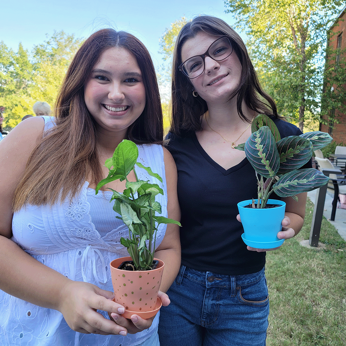 Two students holding the potted plants 