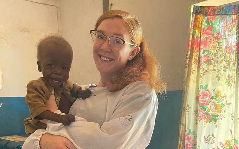 UWG alumna and Peace Corps volunteer Mackenzie Hafer with a child in a Madagascar health clinic