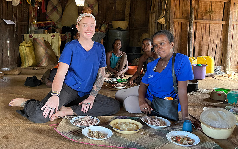 UWG alumna and Peace Corps volunteer Mackenzie Hafer with a family at mealtime in Madagascar