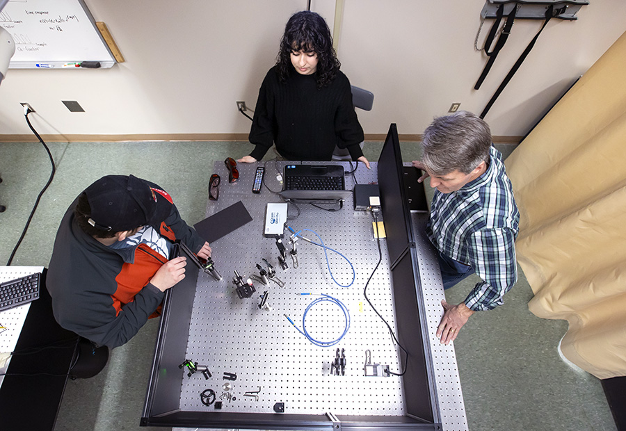 Students working in the physics lab with faculty member