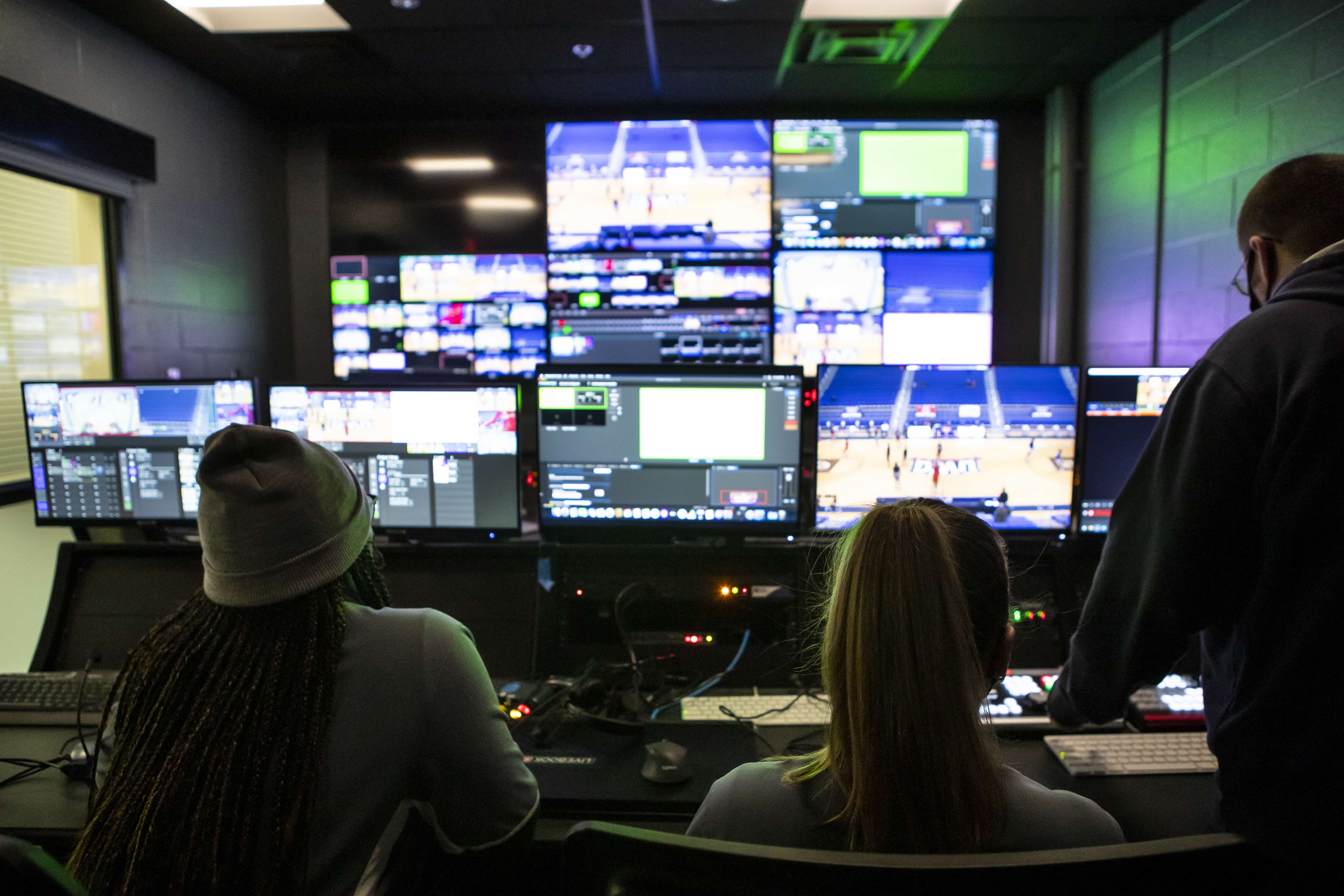 Students sitting in the control room, in front of a number of television screens and control boards.