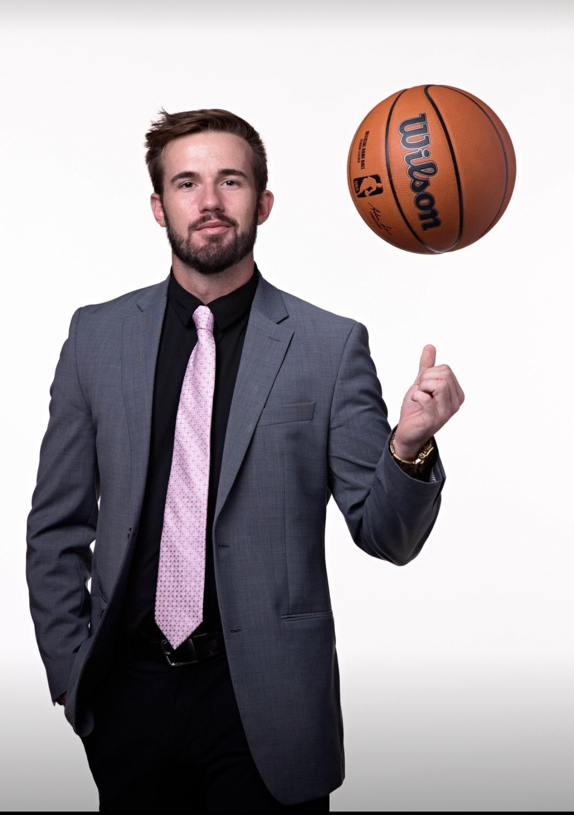 Drew Gentry wearing a suit and spinning a basketball on his finger.