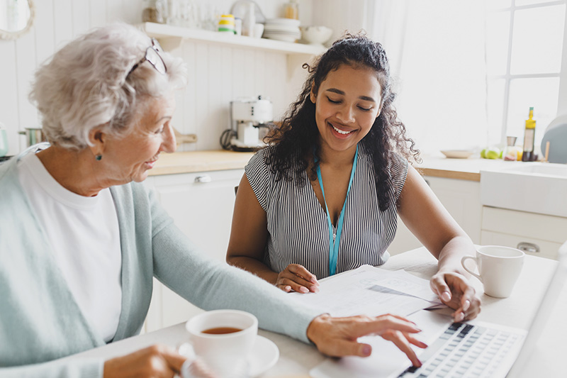 Young women helping elderly woman on a laptop