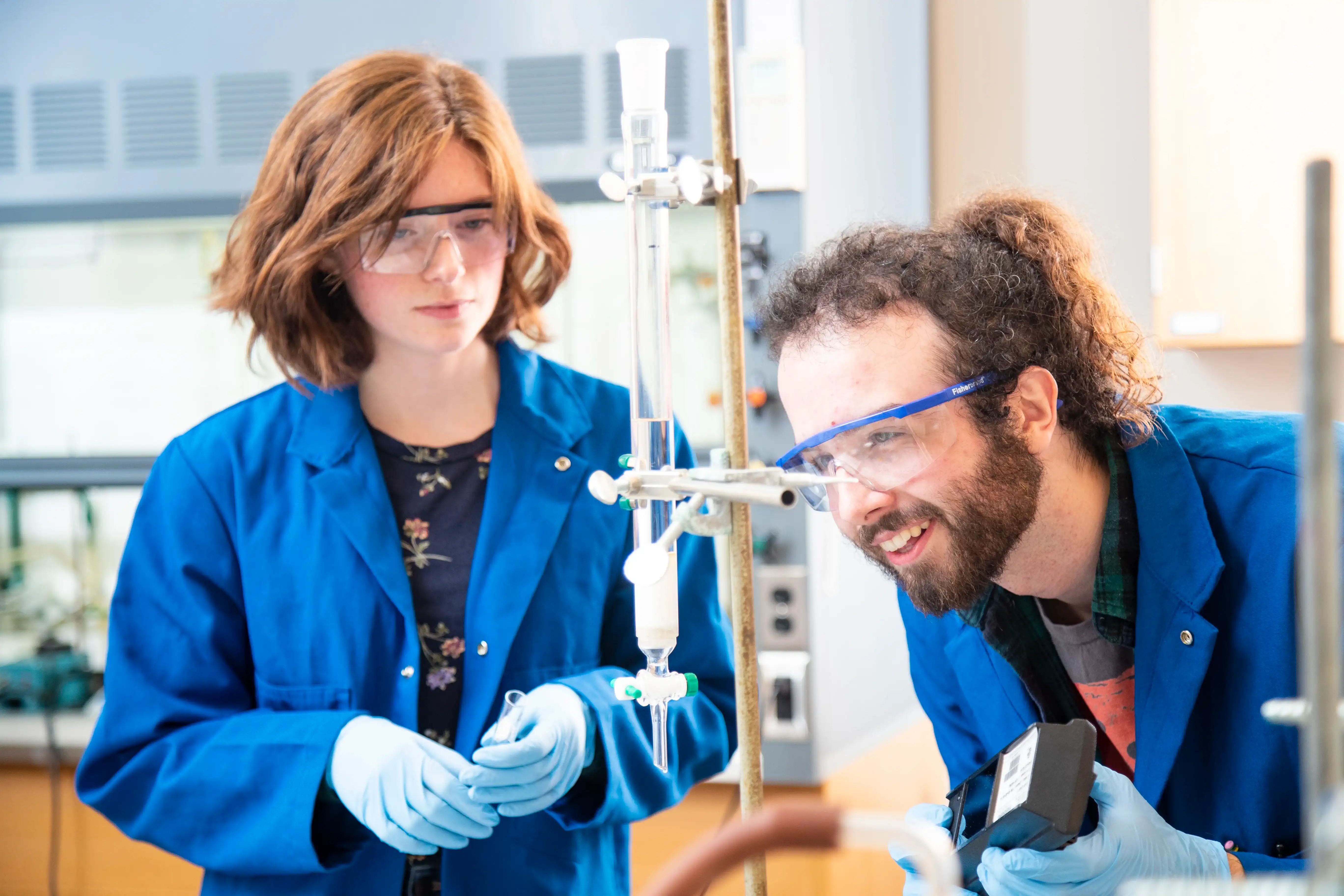 Student wearing lab coats working together in a science lab.