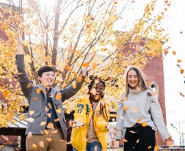 Students smiling with fall leaves.