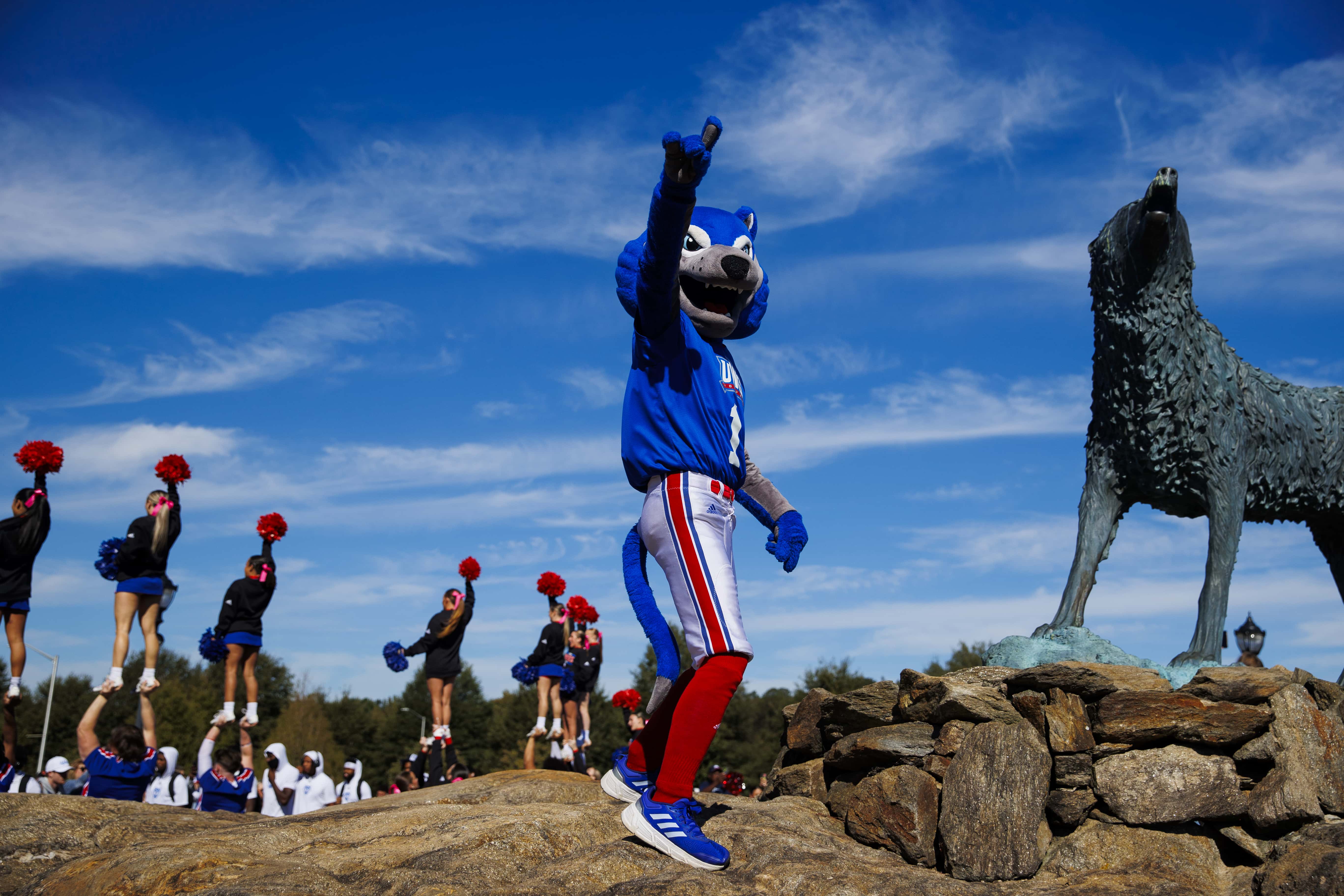 Wolfie and UWG Cheerleaders standing and cheering outside at Wolf Plaza.