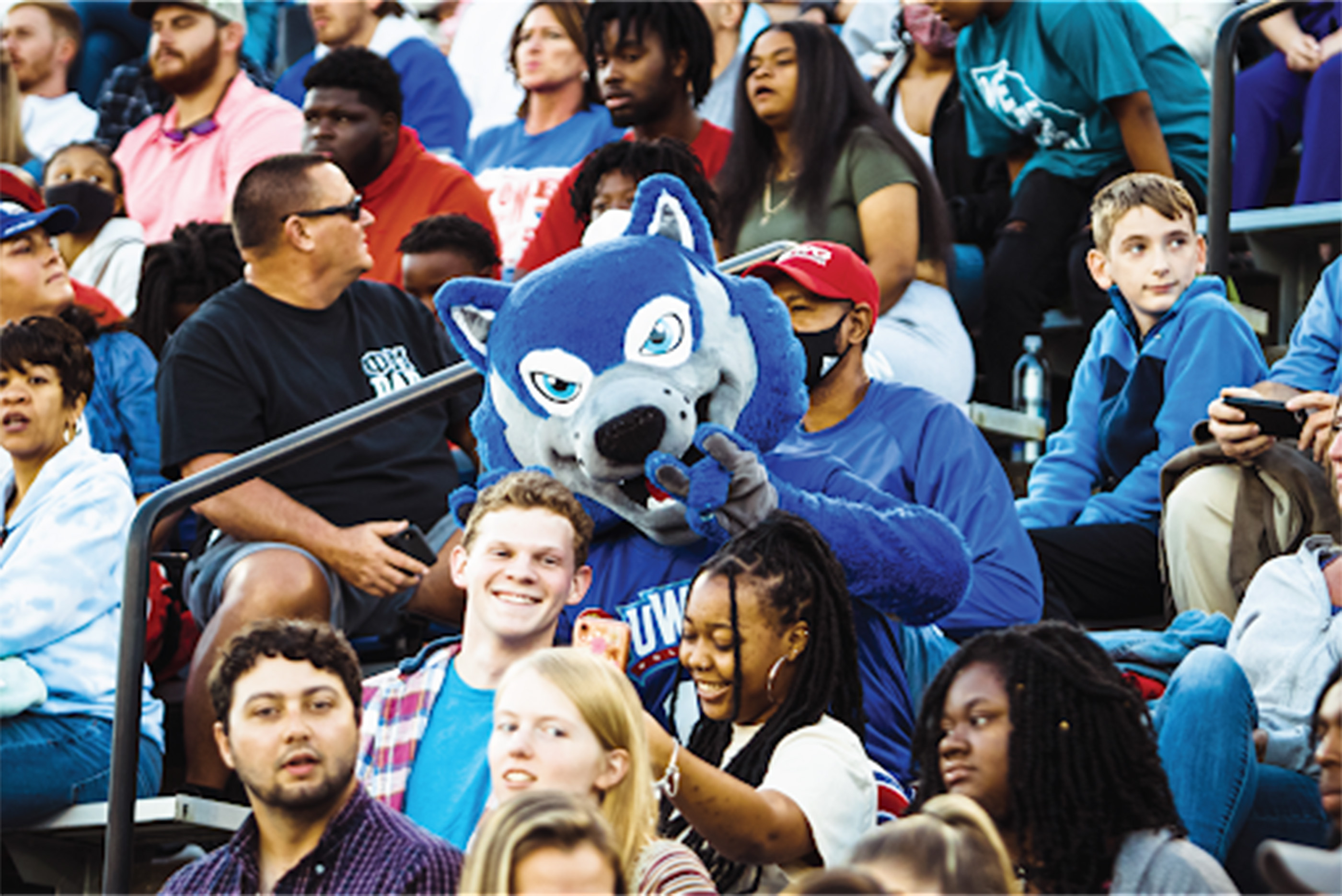wolfie in a crowd with students and parents and friends at the stadium