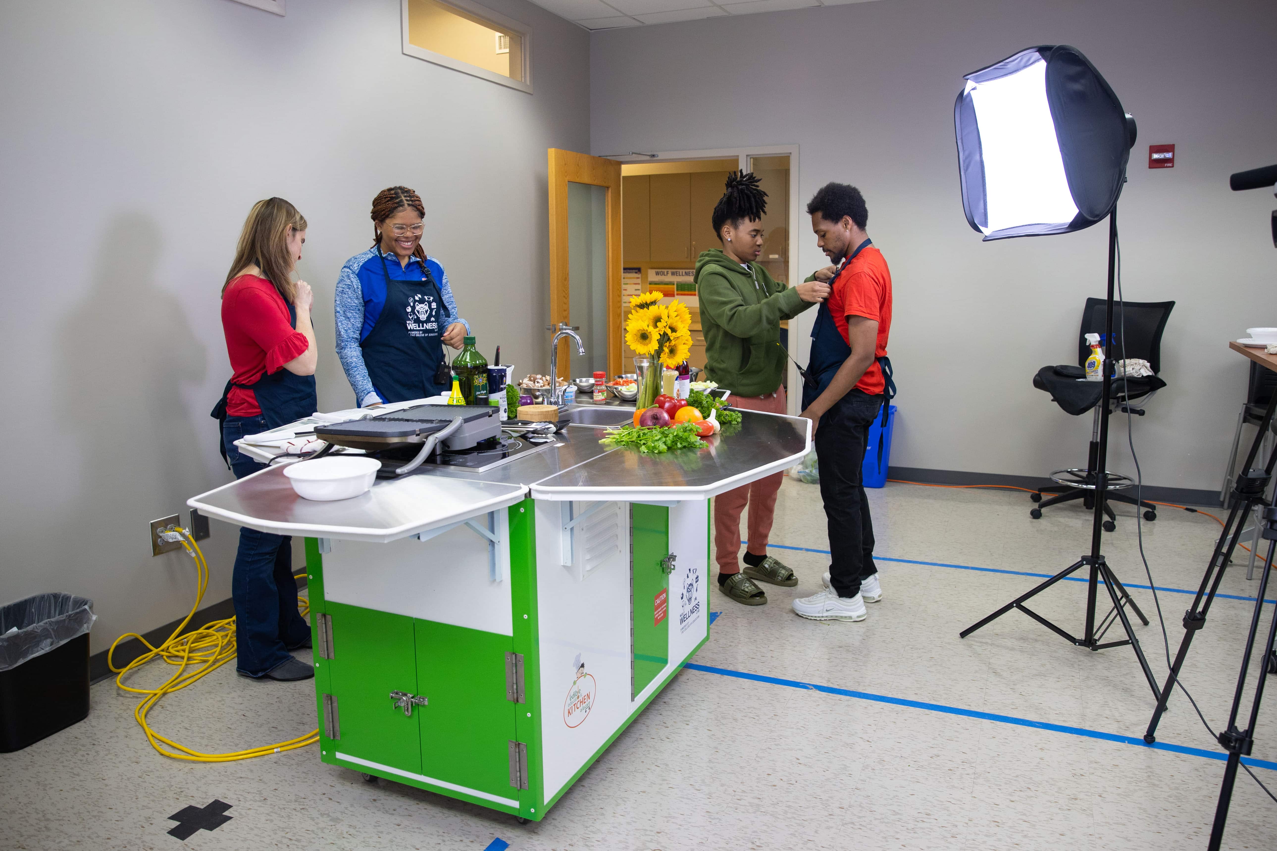 Matthew Cash sets up students and faculty with mics to film cooking demonstration.