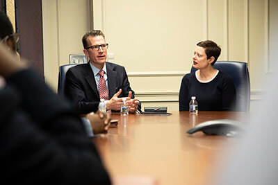 Drs. Brendan and Tressa Kelly speak with student leaders at a conference table.