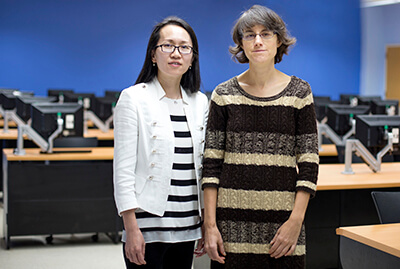 Dr. Remshagen and Dr. Yang stand together in a classroom filled with computers at desks.