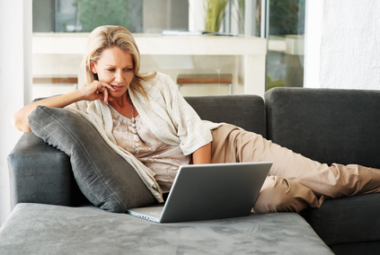 Woman sitting on couch with laptop.
